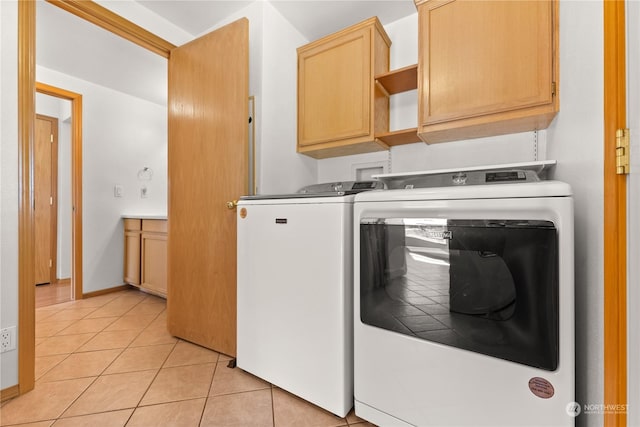 laundry area featuring washer and dryer, cabinets, and light tile patterned flooring