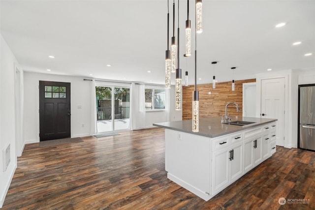 kitchen with stainless steel fridge, a kitchen island with sink, sink, pendant lighting, and white cabinets