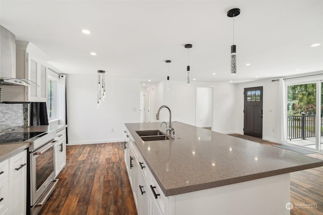 kitchen featuring a spacious island, wall chimney range hood, electric stove, pendant lighting, and white cabinets