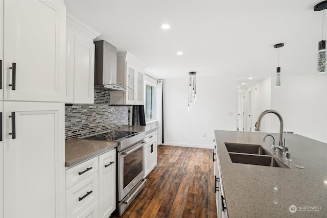 kitchen featuring pendant lighting, white cabinets, high end stainless steel range, wall chimney exhaust hood, and light stone countertops