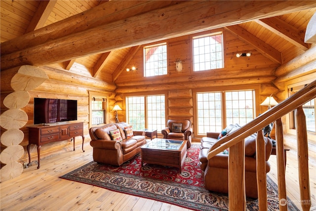 living room with beamed ceiling, light hardwood / wood-style flooring, rustic walls, high vaulted ceiling, and wooden ceiling