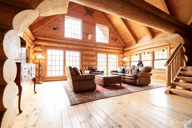 living room featuring wood ceiling, rustic walls, light wood-type flooring, beam ceiling, and high vaulted ceiling