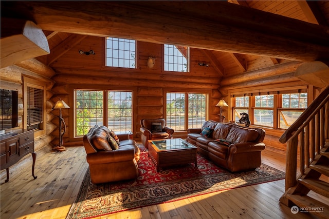 living room with light hardwood / wood-style flooring, beam ceiling, and rustic walls