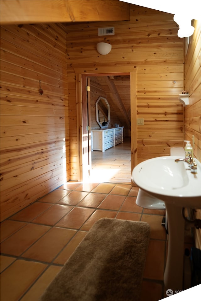 bathroom with tile patterned flooring and wooden walls