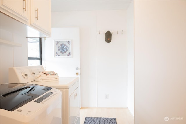 laundry area with separate washer and dryer and cabinets