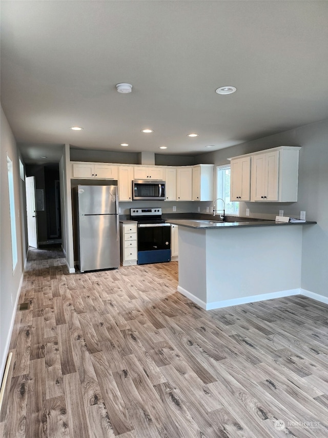 kitchen featuring kitchen peninsula, white cabinets, stainless steel appliances, and light wood-type flooring