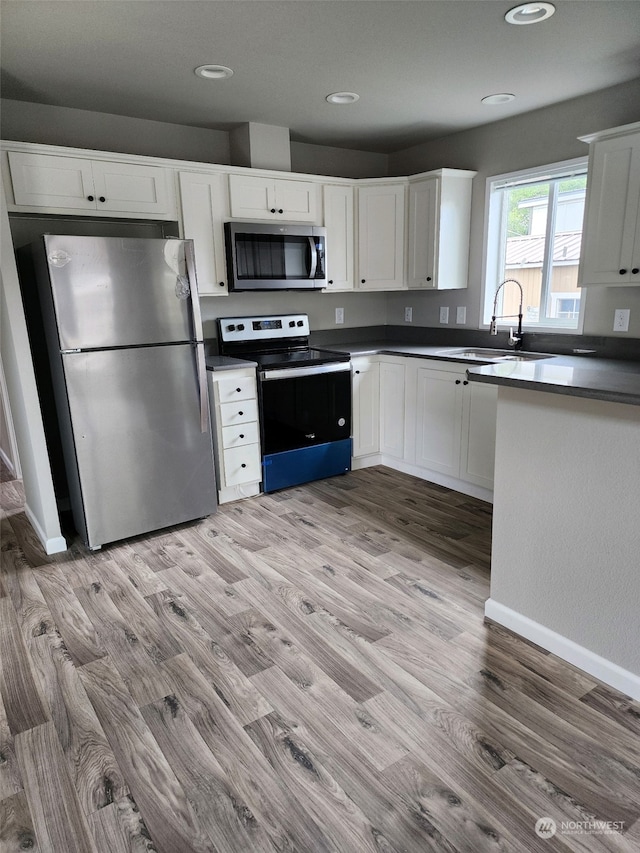 kitchen with sink, white cabinets, light hardwood / wood-style floors, and appliances with stainless steel finishes