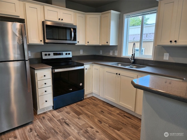 kitchen with wood-type flooring, sink, white cabinetry, and stainless steel appliances