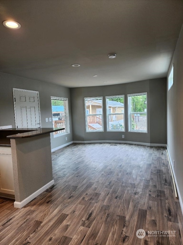 unfurnished living room with a wealth of natural light and dark wood-type flooring