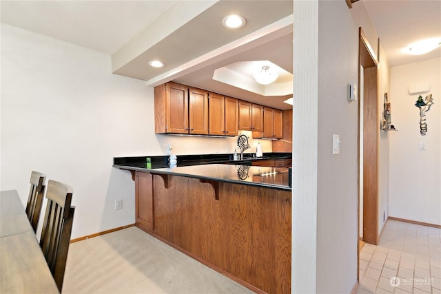 kitchen with a raised ceiling, kitchen peninsula, and a kitchen breakfast bar