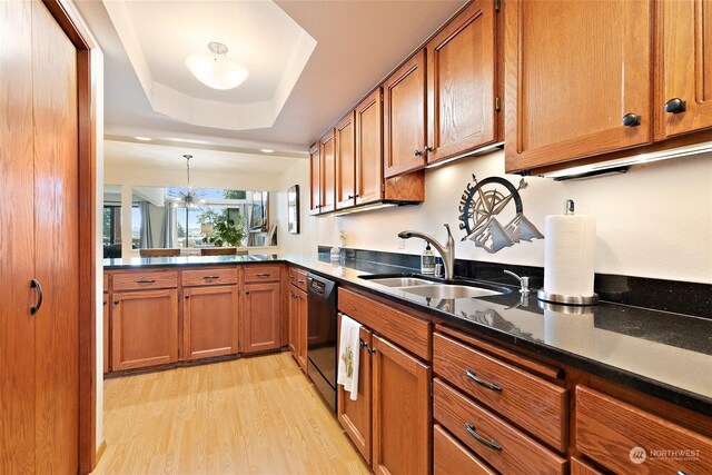 kitchen featuring pendant lighting, a raised ceiling, sink, an inviting chandelier, and black dishwasher