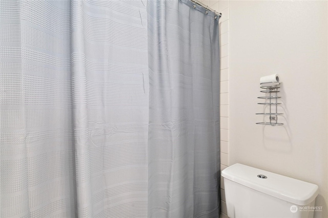 bathroom featuring toilet and curtained shower