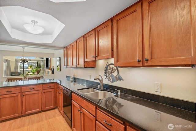 kitchen featuring sink, a raised ceiling, dishwasher, a notable chandelier, and light hardwood / wood-style floors