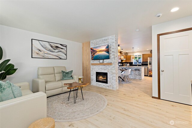 living room featuring brick wall, light hardwood / wood-style floors, and a fireplace