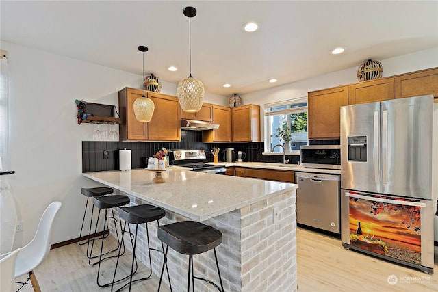 kitchen with hanging light fixtures, decorative backsplash, a breakfast bar area, and appliances with stainless steel finishes