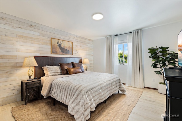 bedroom featuring wooden walls and light hardwood / wood-style flooring