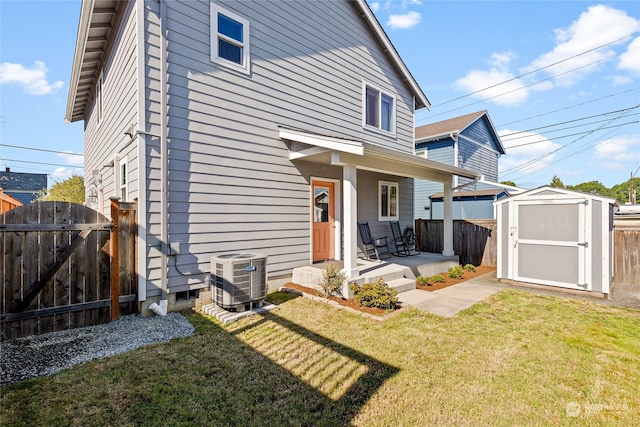 rear view of house with a yard, central air condition unit, and a storage unit