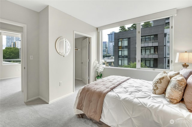 bedroom featuring light carpet and a walk in closet