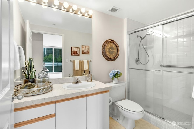 bathroom featuring tile patterned floors, a shower with door, vanity, and toilet