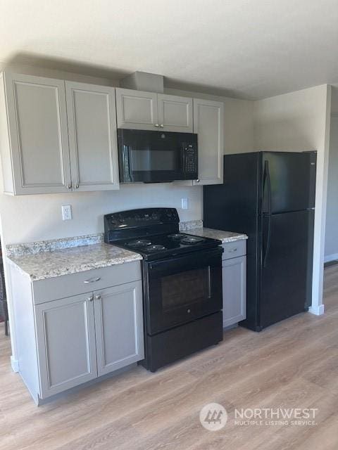 kitchen featuring gray cabinetry, light wood-style flooring, and black appliances