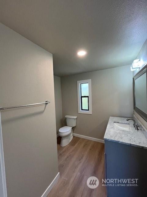 bathroom featuring vanity, wood finished floors, toilet, and baseboards