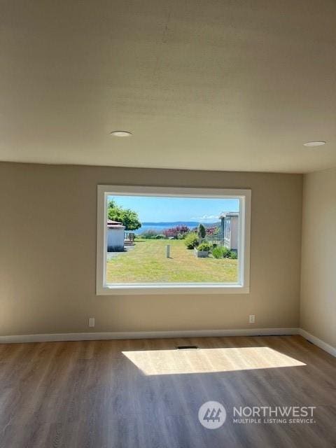 spare room with baseboards and wood finished floors