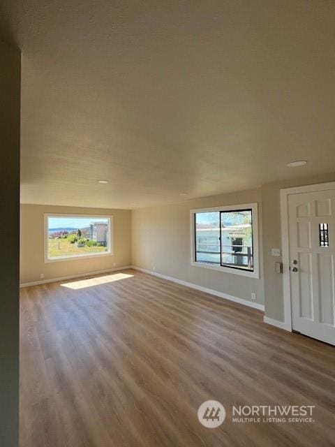 unfurnished living room with baseboards and wood finished floors