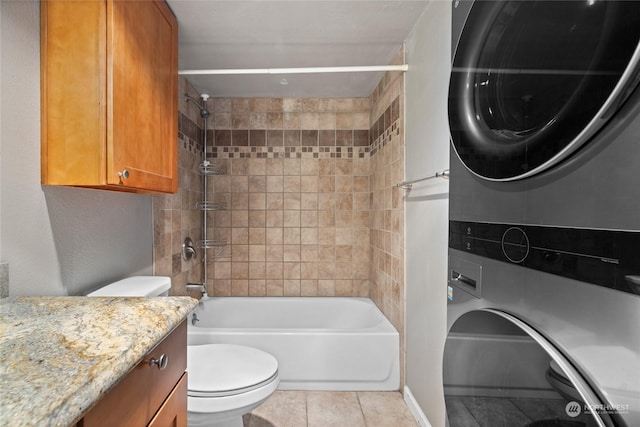 full bath with toilet, stacked washer / dryer, vanity, tub / shower combination, and tile patterned floors