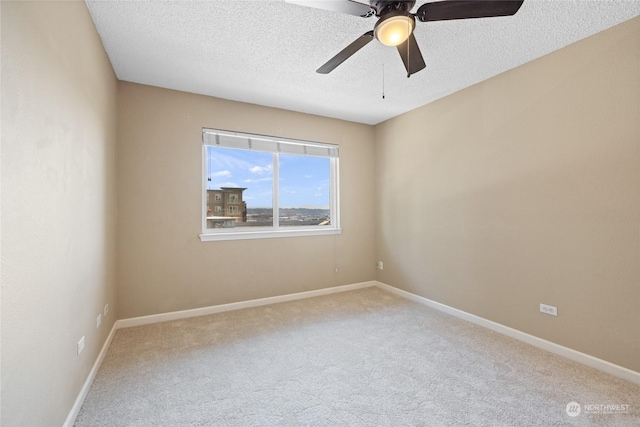 carpeted spare room featuring a ceiling fan, baseboards, and a textured ceiling