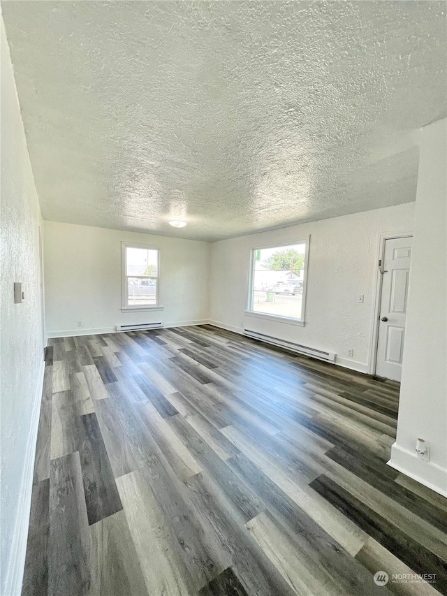 1579 2nd Ave N, Okanogan, WA 98840 - unfurnished living room with a baseboard heating unit, a textured ceiling, wood finished floors, and baseboards