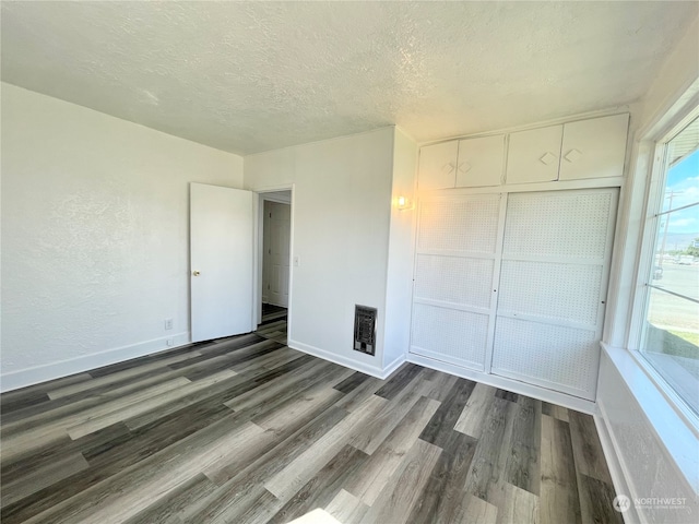 unfurnished bedroom featuring a textured ceiling, a closet, and dark wood-type flooring