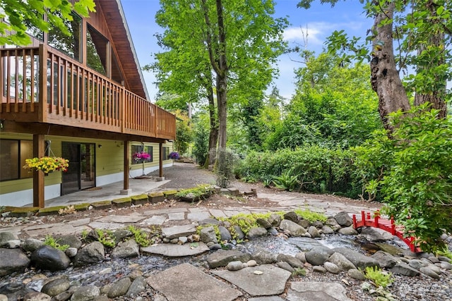 view of yard featuring a wooden deck and a patio