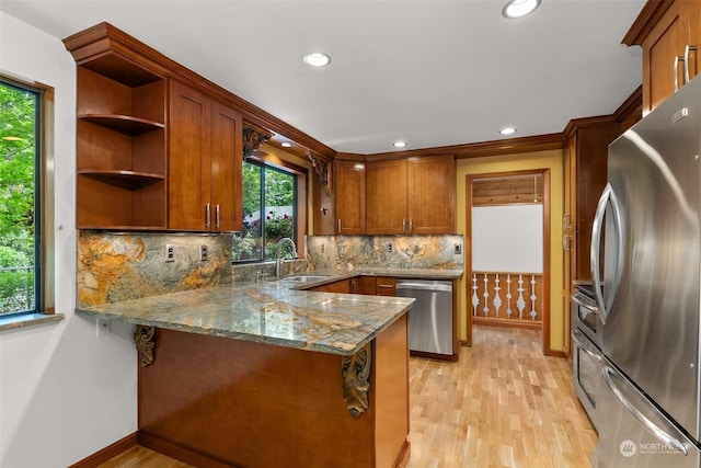 kitchen featuring appliances with stainless steel finishes, backsplash, light stone counters, light hardwood / wood-style floors, and kitchen peninsula