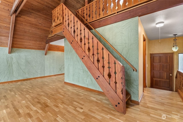 stairs featuring hardwood / wood-style floors, wood ceiling, and lofted ceiling with beams