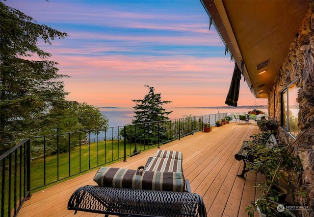 deck at dusk featuring a water view