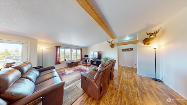 living room with vaulted ceiling with beams, a textured ceiling, and wood-type flooring