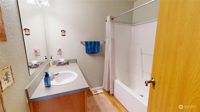 bathroom featuring hardwood / wood-style floors, oversized vanity, and shower / tub combo