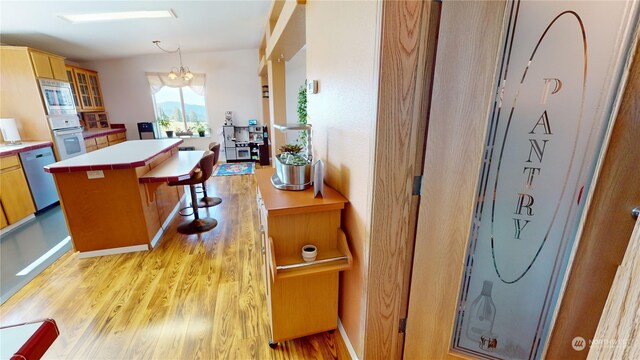 interior space featuring a kitchen breakfast bar, light hardwood / wood-style floors, dishwasher, stainless steel microwave, and oven