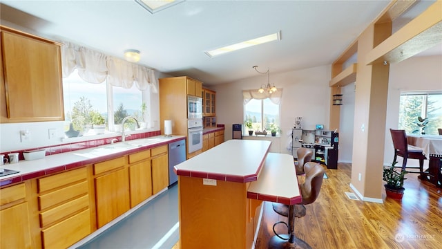 kitchen featuring stainless steel appliances, light wood-type flooring, a center island, and tile countertops