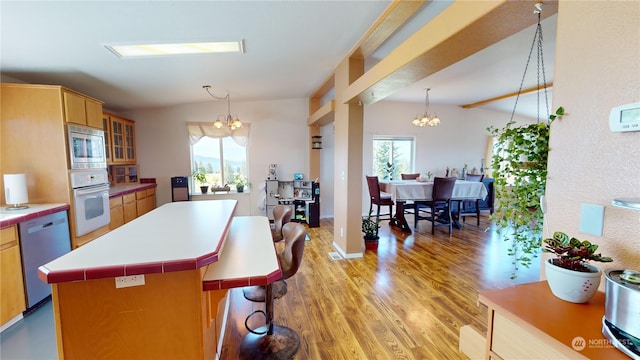 kitchen featuring a kitchen island, stainless steel microwave, a notable chandelier, oven, and dishwasher