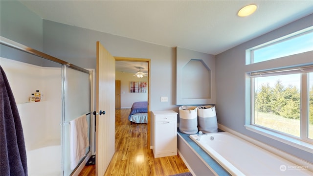 bathroom featuring ceiling fan, a healthy amount of sunlight, hardwood / wood-style flooring, and independent shower and bath