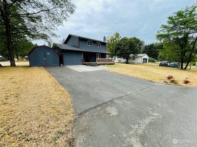 front facade featuring a front lawn, an outbuilding, and a deck