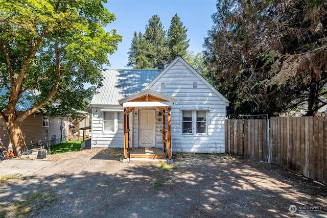 bungalow-style house featuring metal roof and fence