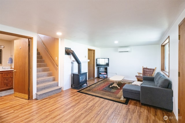 living room featuring a wall mounted air conditioner, light hardwood / wood-style flooring, and a wood stove