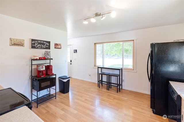 interior space with track lighting, black fridge, and light wood-type flooring