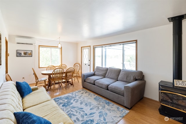 living room featuring a wall mounted AC, wood-type flooring, and a wood stove