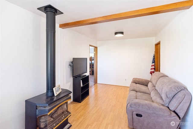 living room featuring beamed ceiling, a wood stove, and light wood-type flooring