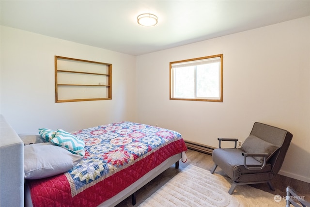 bedroom with baseboard heating and hardwood / wood-style floors