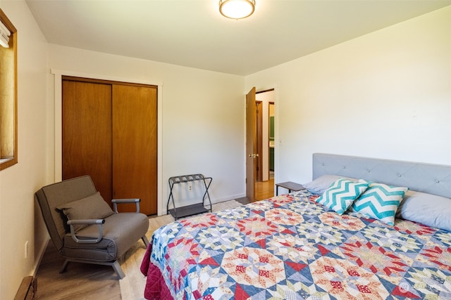 bedroom with wood-type flooring, a closet, and a baseboard radiator