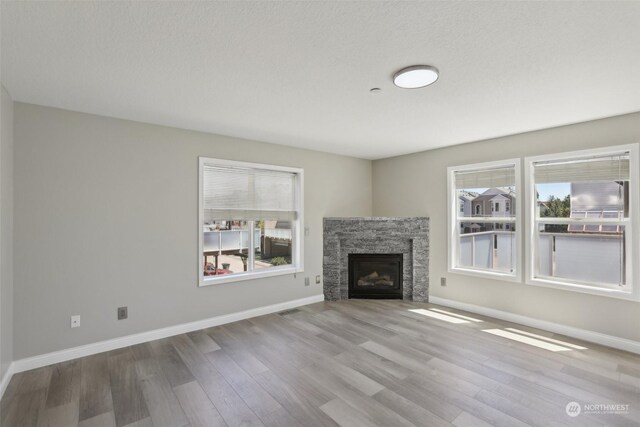 unfurnished living room featuring a stone fireplace and hardwood / wood-style floors